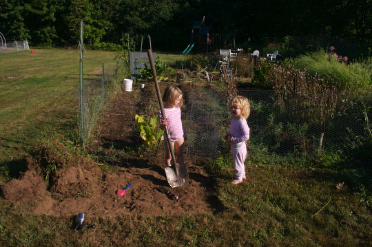 Charlotte and Bea help excavate the spot for the raised bed and mini hoop house.